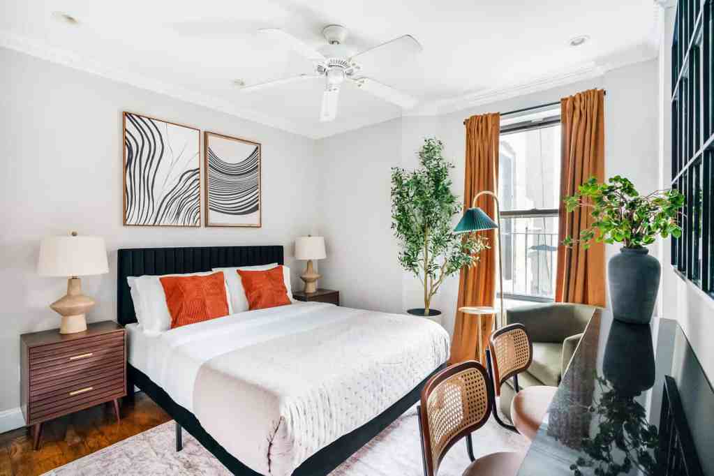 Stylish bedroom with a large bed, artwork, and natural light from windows.