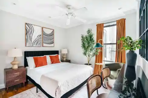 Stylish bedroom with a large bed, artwork, and natural light from windows.