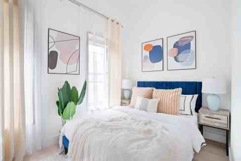 Contemporary bedroom with abstract wall art and cozy bedding.