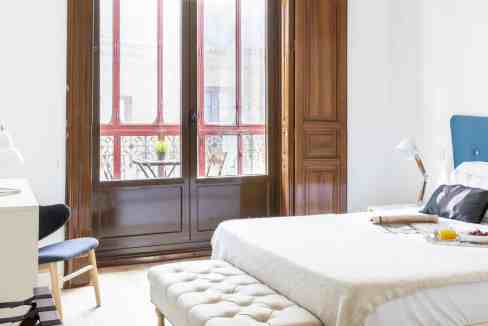 Bright bedroom with large windows, wooden accents, and modern decor in Sol Mirror Loft.
