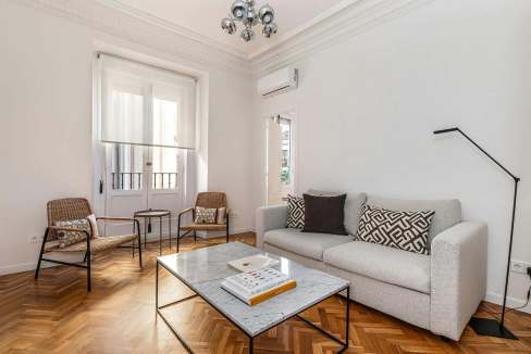 Bright and modern living room with white walls and wooden flooring.