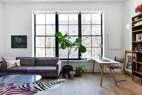 Spacious living room with large window, sofa, and bookshelf for modern apartment.