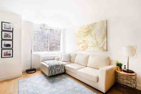 Bright living room with white sofa, large window, and artwork in Sutton Skyline Loft.