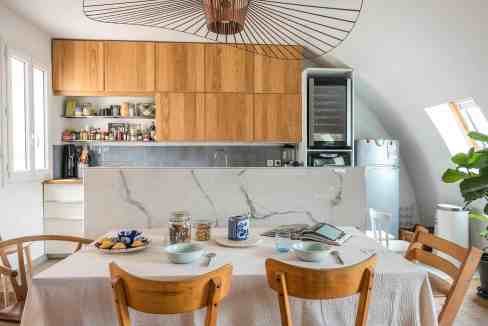 Bright modern kitchen with wooden cabinets and marble island.