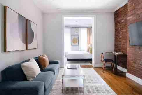 Modern living room with sofa, artwork, and brick wall in SoHo Loft.