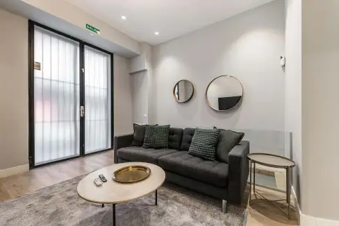 Contemporary living room with sofa, mirrors, and side table in serviced apartment.