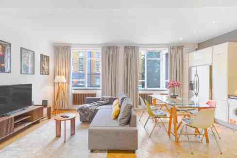 Spacious living room with large windows, modern furniture, and bright decor in Farringdon Gold Suite.