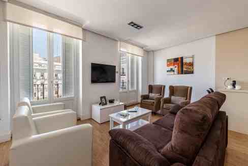 Spacious living room with large windows and modern furniture in Sol Balcony Suite.