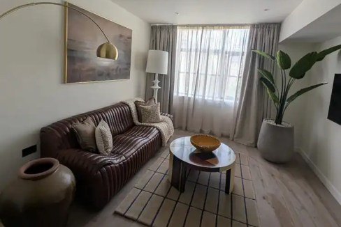 Stylish living room with sofa, coffee table, and large window at Craftworks Barbican Suites.