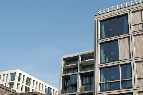 Contemporary apartment building in Amsterdam Noord with large windows and wooden facade.