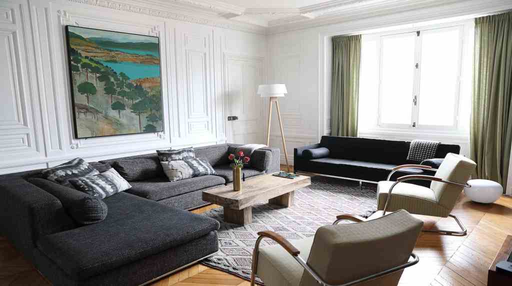 Spacious living room with white walls, large windows, and modern furniture.