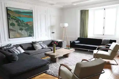 Spacious living room with white walls, large windows, and modern furniture.