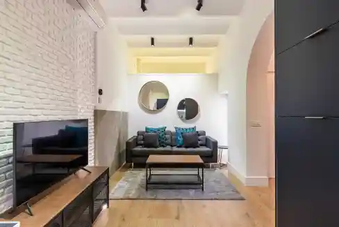 Stylish living room with sofa, mirrors, and modern decor in serviced apartment.