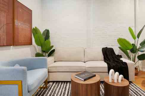 Contemporary living room with beige sofa, blue armchair, and green plants.