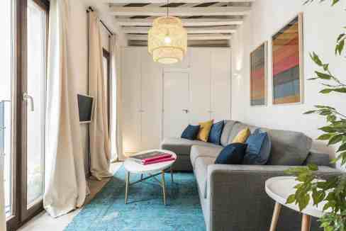 Bright living room with large windows, cozy sofa, and stylish decor.