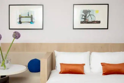 Contemporary bedroom with artwork, flowers, and decorative pillows.