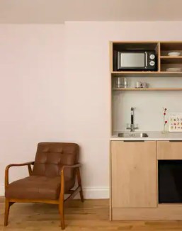 Compact kitchen with microwave, sink, and open shelving in a serviced apartment.