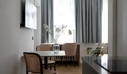 Bright and airy living space in a serviced apartment with large windows and elegant decor.