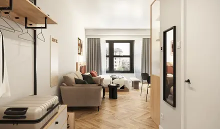 Modern serviced apartment interior in Dortmund city center with sofa and large window.