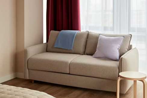 Modern beige sofa with cushions in a bright living room setting.