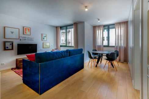Modern Lisbon serviced apartment living room with blue sofa and dining area.