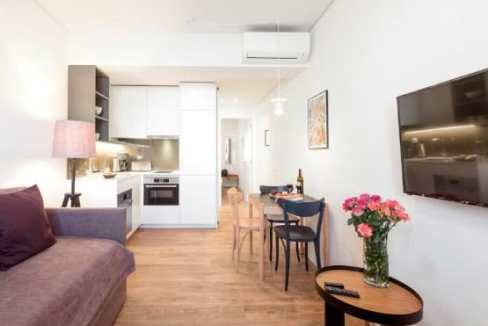 Modern serviced apartment living room with minimalist decor and wooden flooring.