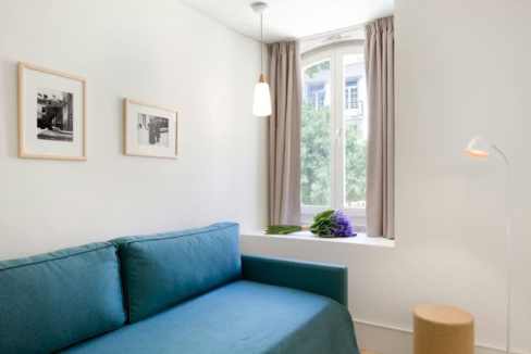 Modern living room with blue sofa and large window in Lisbon.