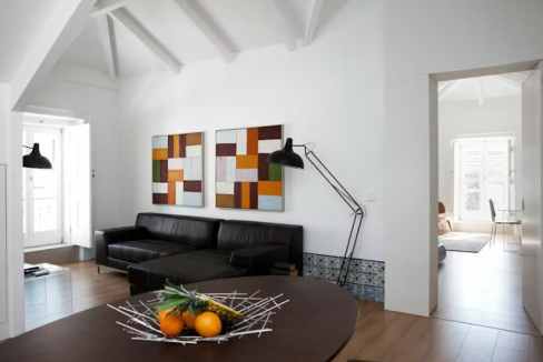 Modern living room with black sofa and colorful abstract art on white walls.