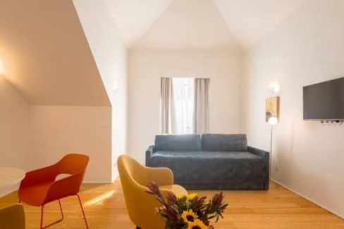 Bright, modern living room with colorful chairs and a blue sofa in Lisbon apartment.
