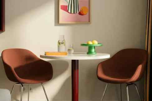 Modern dining area with two brown chairs and a round white table.