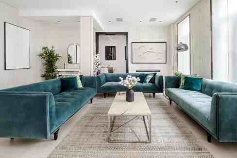 Elegant modern living room with teal sofas and minimalist decor.