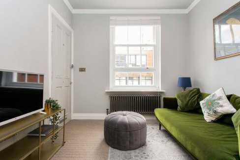 Bright living room with green velvet sofa and large window.