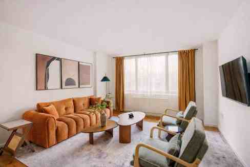 Spacious living room with a large sofa, armchairs, and a wall-mounted TV.
