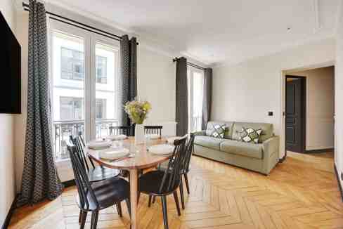 Bright living and dining area in a Paris serviced apartment with modern decor.