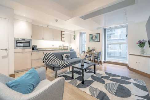 Bright, modern living room with sofa, coffee table, and large windows.