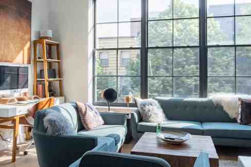 Bright living room with large windows, blue sofas, and cozy cushions.