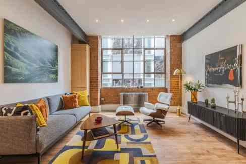 Modern living room in Shoreditch warehouse with stylish furniture and large windows.