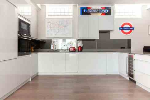Contemporary white kitchen with appliances and London Underground decor.