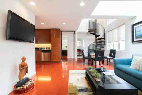 Bright, modern living space with a spiral staircase and large windows.