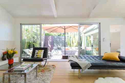 Modern living room with large glass doors opening to outdoor patio.