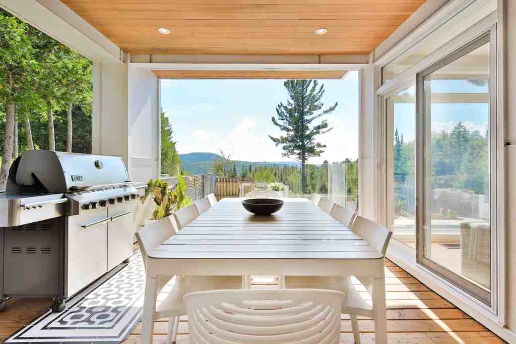 Bright sunroom with large windows overlooking trees and mountains.