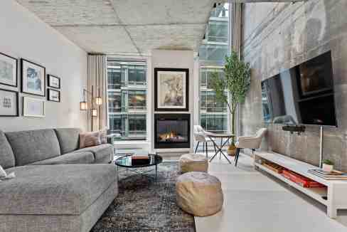 Contemporary living room with fireplace, large windows, and stylish decor.