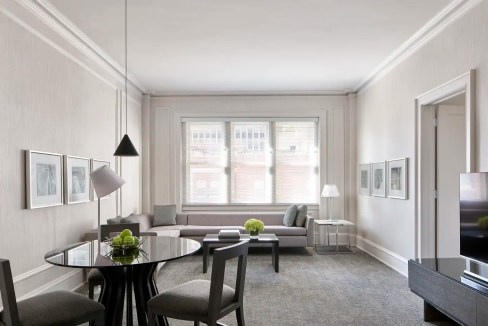 Bright and spacious living room in a serviced apartment with large windows and contemporary decor.