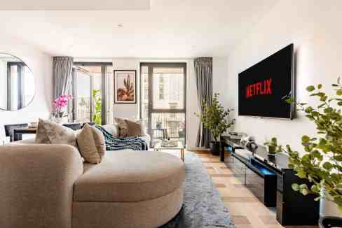 Contemporary living room with sofa, TV, and balcony view at Wapping Tower Vista.