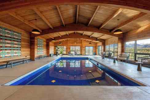 Indoor swimming pool with wooden ceiling and large windows at Cedar Highlands Retreat.