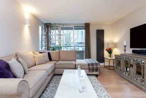 Spacious living room with sofa, TV, and large window in Belsize Park.