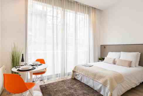 Bright bedroom with large window, white bedding, and cozy decor.