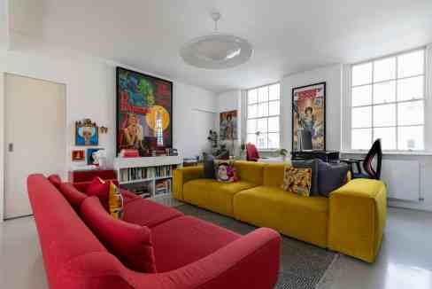 Modern living room with colorful sofas and vintage posters in Marylebone.