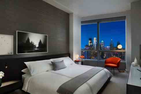 Elegant bedroom with city skyline view and contemporary decor.