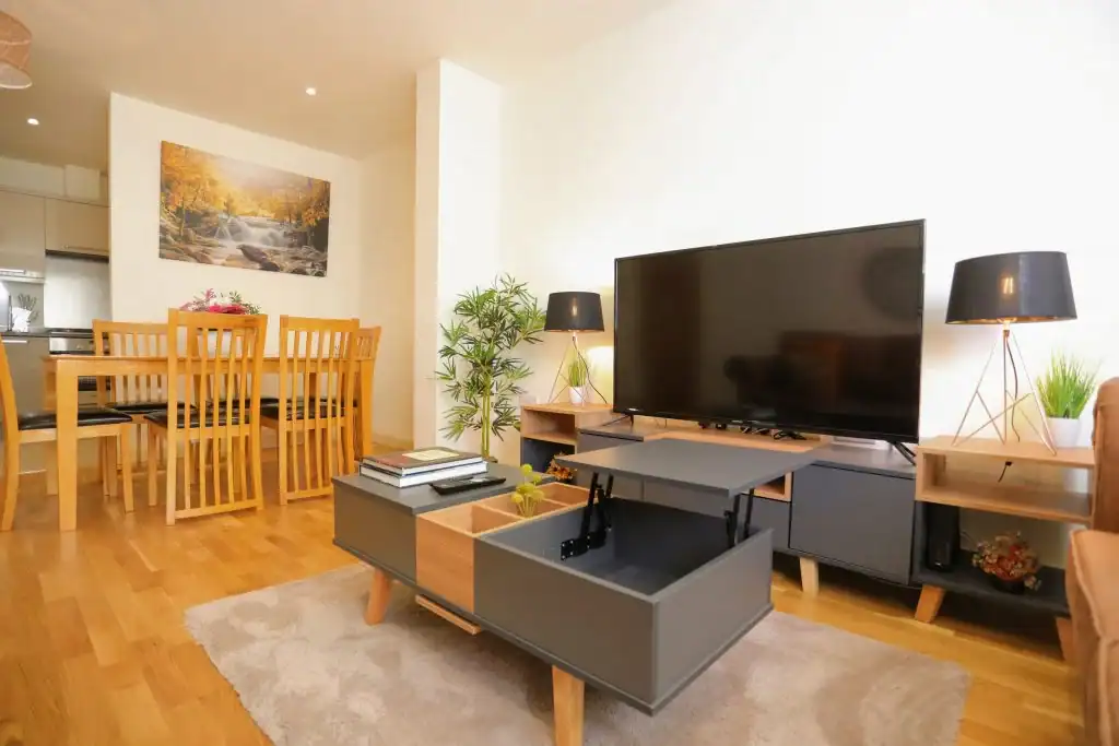Contemporary living room with TV, wooden furniture, and decor.